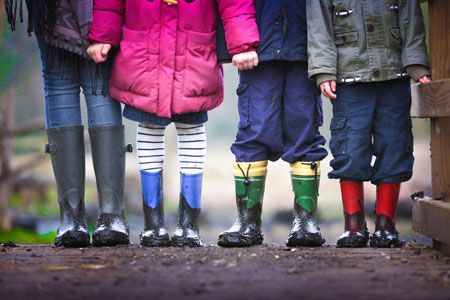 photo des jambes de 4 enfant dans des bottes de pluie