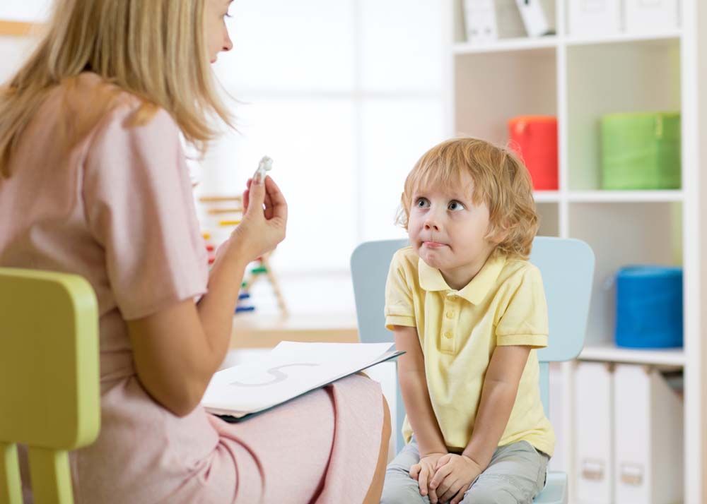 image d'un enfant assis face à une personne avec qui il échange. 