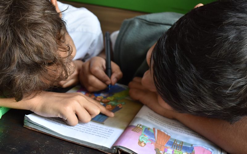 photo de deux enfants qui lisent et écrivent sur un livre